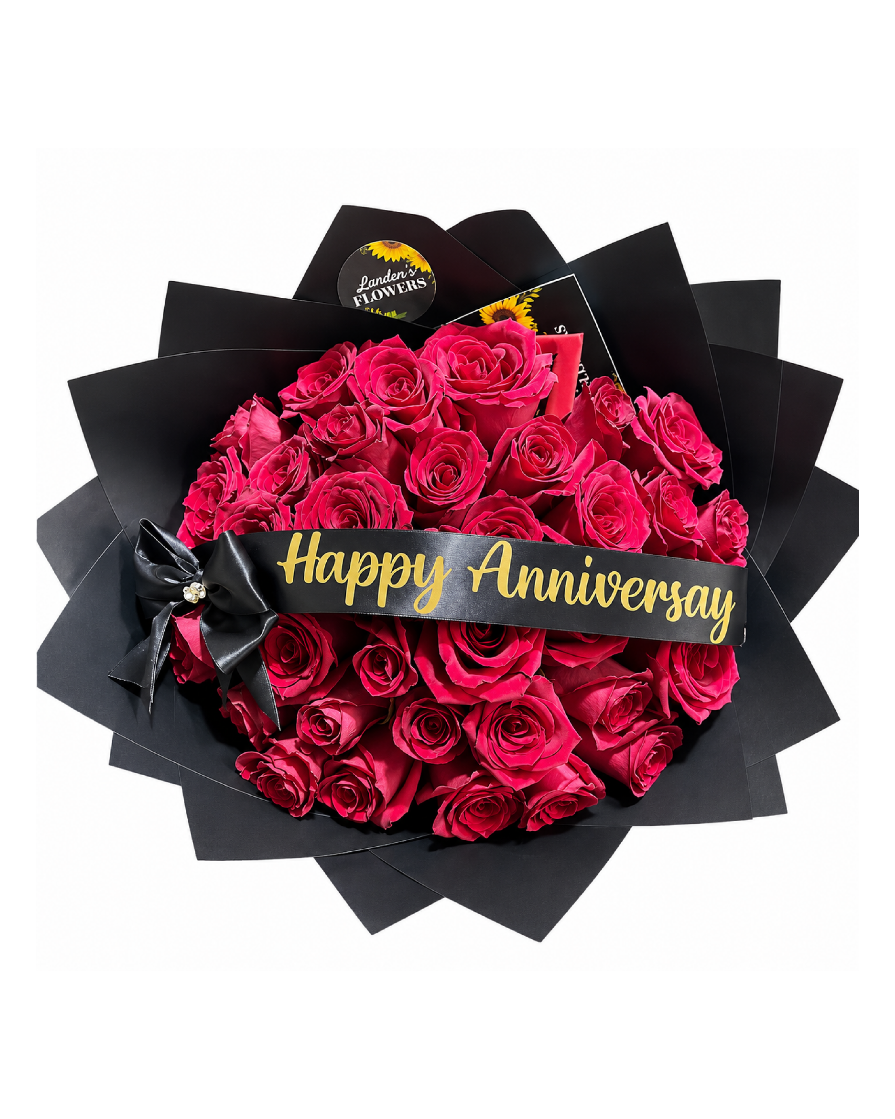 Bouquet of red roses with a 'Happy Anniversary' ribbon in a black box, featuring a brand logo.