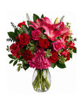 Bouquet of red and pink flowers in a clear vase on a white background